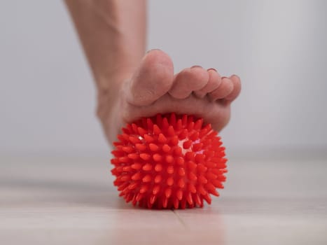 Close-up of a woman's foot on a massage ball with spikes.