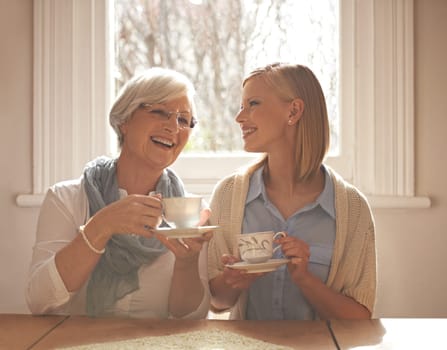 Family, happy woman and senior mother drinking tea at breakfast, bonding and smile in house. Laughing, elderly mom and daughter with coffee cup at table, conversation or funny people at home together