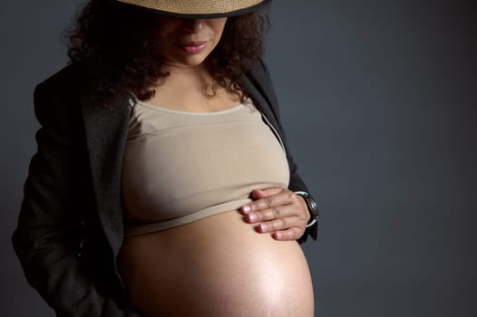 Close-up portrait of young beautiful pregnant woman gently caressing her belly, enjoying her happy carefree pregnancy