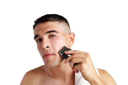 Handsome young man shaving face with electric razor on white background