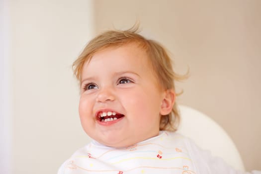Baby, smile and laughing for fun, play and watch of game and joke as sitting in high chair in home. Happy, young or child for joy, positive or humor for healthy growth or early childhood development