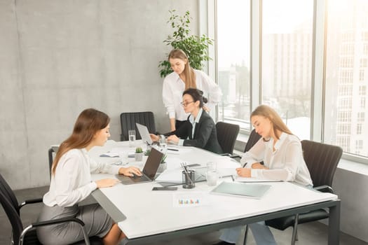 Business women working in modern office with documents and laptops, free space
