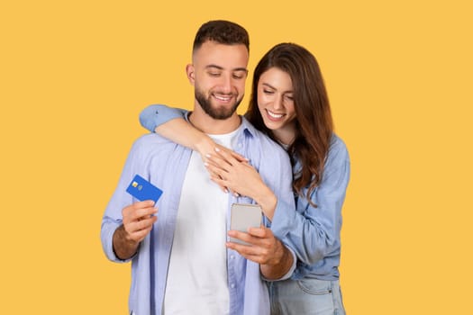 Smiling couple with credit card and smartphone ready to shop