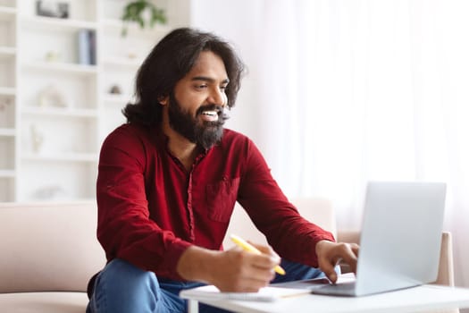 Positive young indian man studying from home