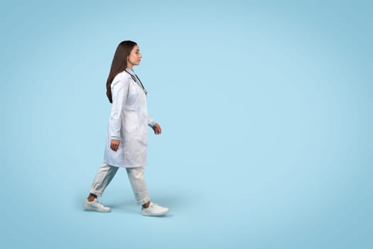 Side view of walking female doctor on blue background, medical ad