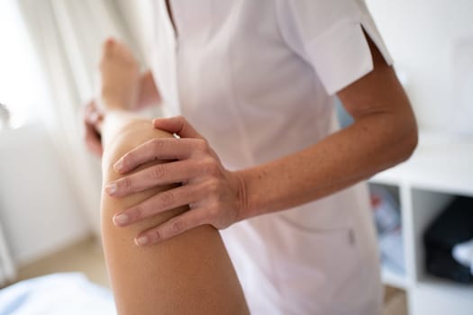 Crop osteopath doing manipulations on leg of woman