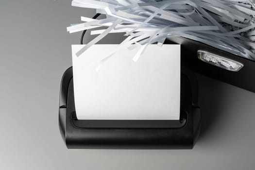 Black paper shredder cutting paper on gray background