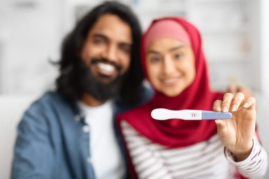 Happy muslim couple showing positive pregnancy test at camera