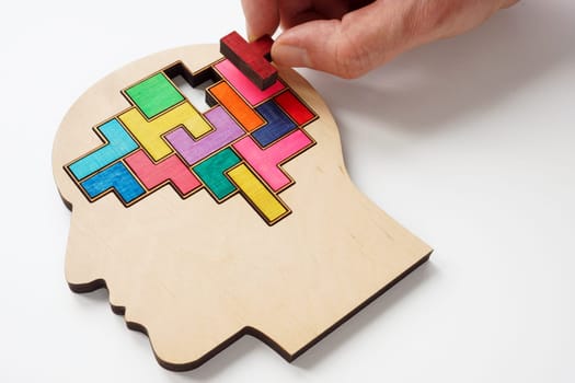 A hand inserts a puzzle piece into the brain. Psychotherapy and psychology concept.