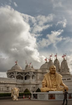 Exterior view of the Neasden temple (BAPS Shri Swaminarayan Mandir) and The gold colored statue depicts the late spiritual leader Pramukh Swami Maharaj.