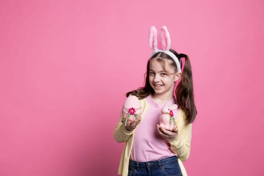 Smiling happy child posing with a pink egg and a rabbit on camera