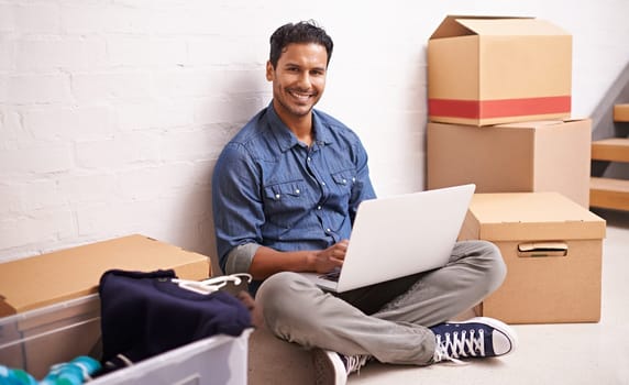 Portrait, man and laptop by boxes in new house, apartment or property for moving, relocating or buying a home. Male person, real estate and mortgage for homeowner with computer, communication or tech.