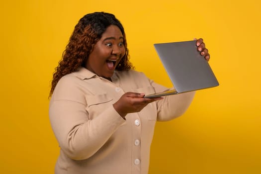 Excited chubby african american woman looking at laptop screen
