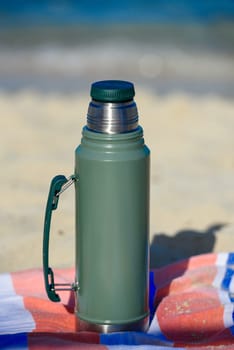 Authentic green Stanley Thermos on the beach in summer