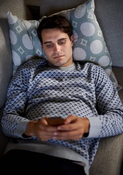 Home, night or above of man on a phone for social media blog, post or network on a sofa. Streaming movie, mobile app or person online for texting on technology for article, email or news to relax.