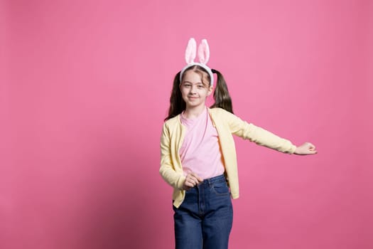 Small carefree girl acting positive with bunny ears on camera