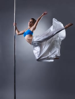 Studio shot of graceful woman turning around pole