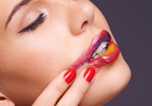 Lipstick, smear and woman with makeup and hand, beauty and red nail polish with cosmetic product in studio. Face, smudge on skin and color for cosmetology with manicure and art on purple background