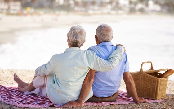Elderly, couple and relax beach for picnic together for summer bonding or travel connection, outdoor or view. Old woman, man and back for vacation holiday at ocean in Hawaii for rest, peace or fun.