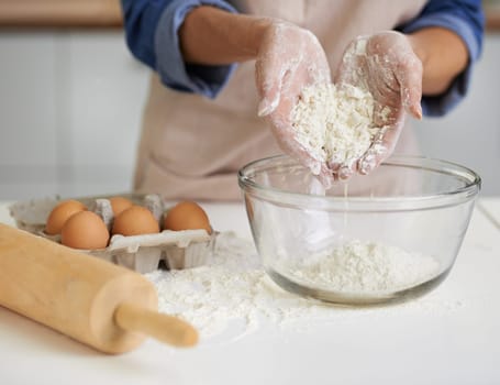 Hands, person and flour with eggs, kitchen and rolling pin for baking. Baker, dough and food with countertop, apron and mixing for recipe preparation and recreation or hobby at home or house