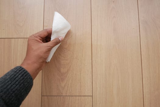 A man's hand washing the floor with a tissue