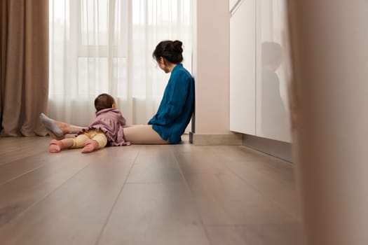 tired woman sitting on the floor with her little child girl