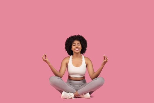 Content african american woman meditating in lotus pose