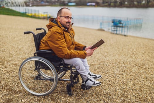Paraplegic handicapped man in wheelchair is reading book