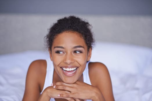 Woman, happy and relax in bedroom in home, inspiration and positive on morning vacation. Young lady, smile and wellness on break on lazy weekend, duvet and pyjamas in cozy bed in modern apartment