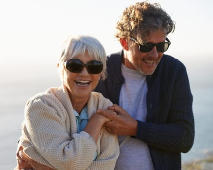 Happy, nature and senior couple with love for travel, tourism and holiday in retirement together. Coast, field and elderly people with smile for summer vacation, bonding and sunset walk in California.
