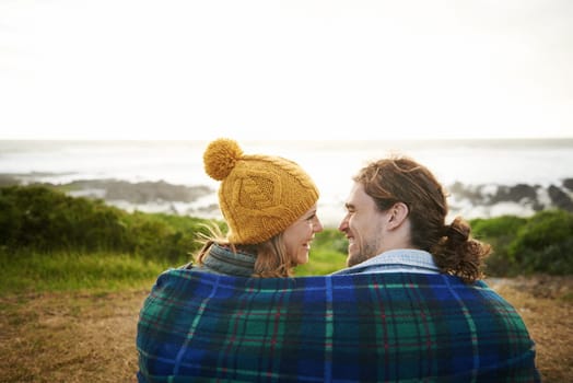 Happy couple, talking or bonding together in nature, blanket or romantic getaway with camping by ocean. Man, woman or love on vacation on weekend break, cape town or travel adventure by sea in sunset.