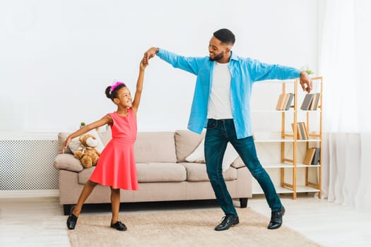 African-american father dancing with little daughter at home