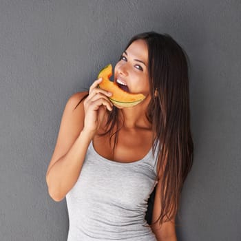 Slice of melon, portrait and woman with smile, nutrition and person on a grey background. Face, model and girl eating a fruit, wellness and mockup space with diet plan and healthy snack with treat.