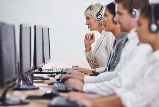 Help desk, phone call and row of women, men and typing on computer at customer support. Headset, telemarketing and client service agent at callcenter for online consultation, team and business people