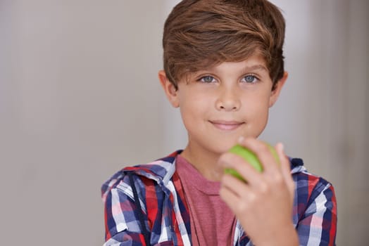 Portrait, apple and boy child in home, eating green fruit as diet, health or nutrition for development. Face, food and natural with confident young teen kid holding organic produce in apartment