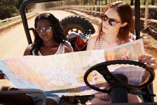 Women, reading and map in car in countryside, lost and travel direction on road trip in nature. Friends, driving or navigation in vehicle on summer holiday, tourist or bonding together on exploration