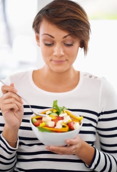 Young woman, diet and salad or healthy food for detox, breakfast and lunch at home. A happy person with green fruits, vegetables and eating lettuce or vegan meal in bowl for nutrition and wellness.