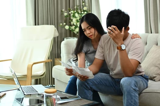 Stressed young couple having financial problems, looking worried about unpaid bank debt.