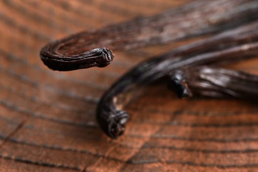 Bourbon Vanilla pods on wooden table, closeup detail on beans tips