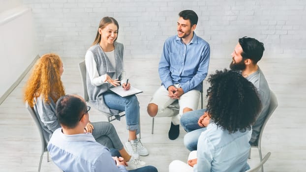 Diverse happy people sitting in trust circle on therapy session