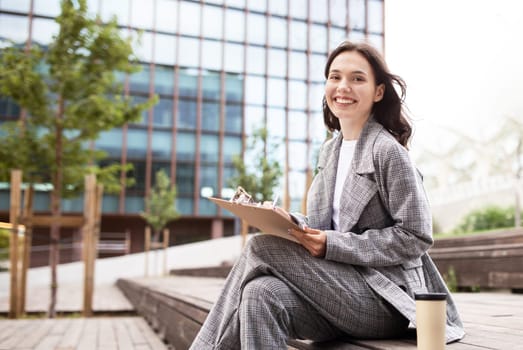 Business Lady Working With Papers Sitting In Urban Area Outdoors
