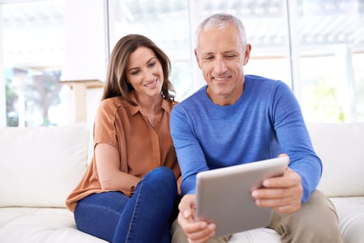 Couple, tablet and happy on sofa to relax with reading, search or app for bonding in home living room. People, woman and mature man on digital touchscreen on lounge couch with web streaming in house