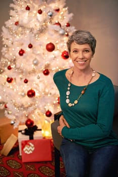 Christmas, tree and portrait of mature woman in home for holiday with presents on vacation. Happy, person and relax on with festive xmas decoration and gift box in living room and enjoy retirement