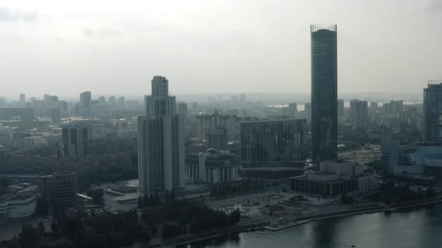 Top view of modern gray city in cloudy weather. Stock footage. Grey cloudy city with river and fog. Cloudy day hanging over modern city