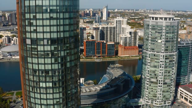 Top view of beautiful business skyscrapers by river. Stock footage. High-rise offices in business center of modern city in summer. Beautiful architecture and landscapes on riverbank in modern city