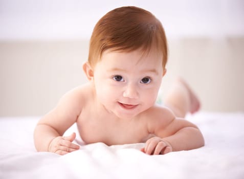 Portrait, bed and happy baby with smile, relax and tummy time or child development in nursery comfort. Girl, infant or newborn wellness in family home for childcare, crawl or kid learning for growth.