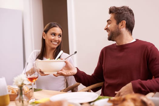 Smile, dinner and couple at table with salad, food, and drinks for celebration in home. Social event, man and woman at thanksgiving lunch together with wine, relax and romantic holiday date in house.
