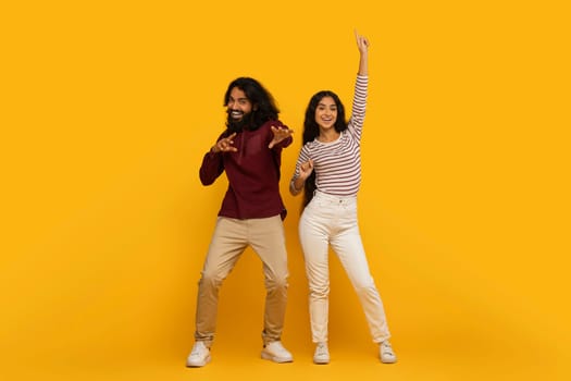 Couple dancing and laughing on a yellow backdrop