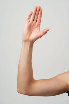Male hand showing five fingers against gray background