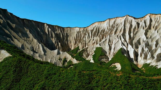 Beautiful aerial of the white cliffs on the south coast of England. Clip. Green summer forested hills and blue sky.